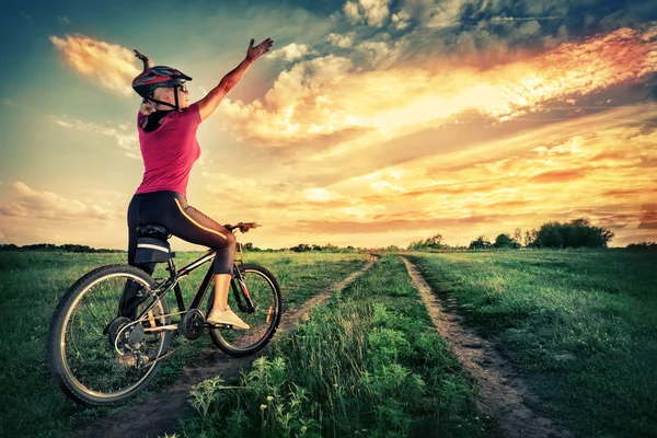 Girl on bicycle pulls her hands to the sky