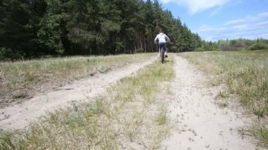 Adam ve çocuk bisikletçiler kumlu yollarda bırakarak