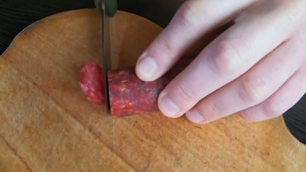 Hands cut sausage on wooden board — Stock Video