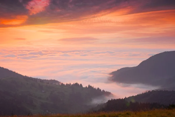 Picchi montuosi sopra le nuvole al tramonto — Foto Stock