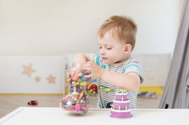 Küçük bir çocuk boncuk ve diğer küçük oyuncaklar ile oynuyor. Çocuk Bahçesi veya oyun eğlence merkezi