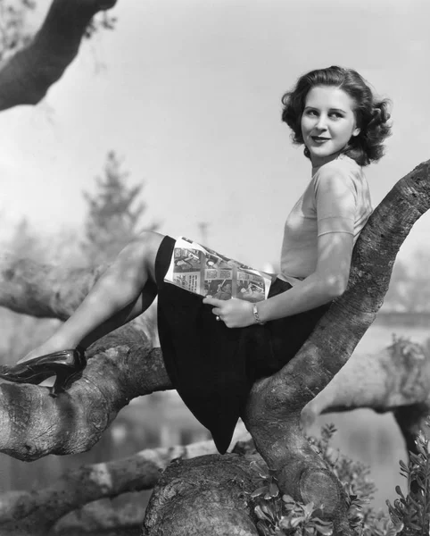 Νεαρή Γυναίκα Που Κάθεται Ένα Δέντρο Διαβάζοντας Ένα Περιοδικό — Φωτογραφία Αρχείου