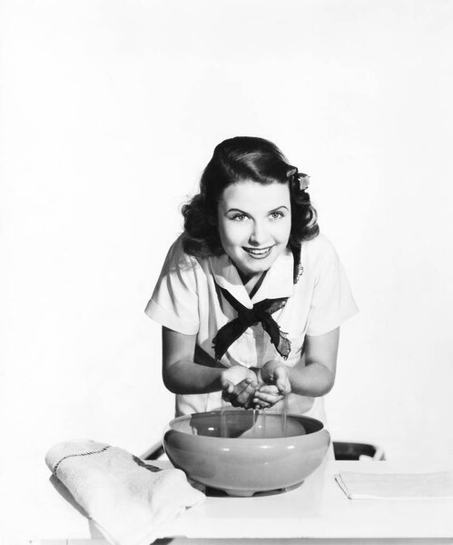 Woman washing her face in a large bowl