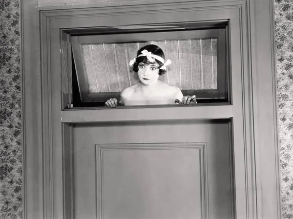 Junge Frau Blickt Aus Der Tür lizenzfreie Stockbilder