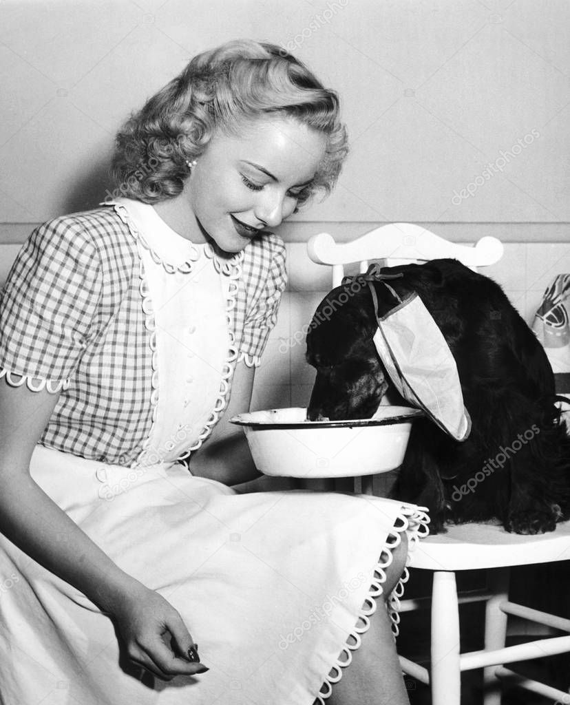 Woman watching her thirsty dog drink from a bowl