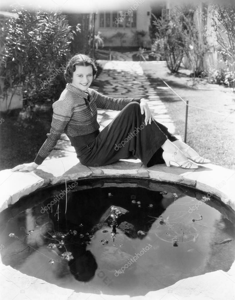 Young woman seated in front of a small reflecting pool