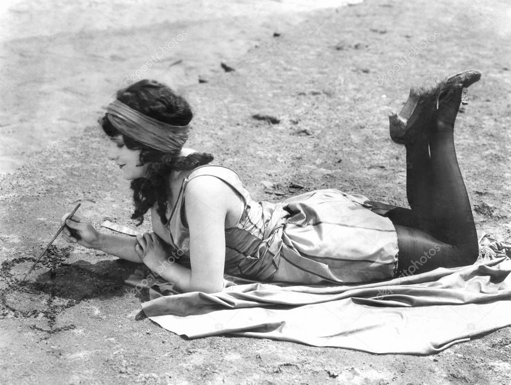 Young woman drawing a heart in the sand