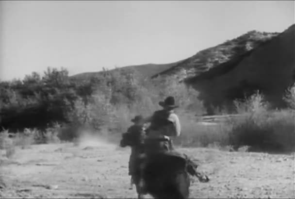 Deux hommes à cheval galopant dans la région montagneuse, années 1930 