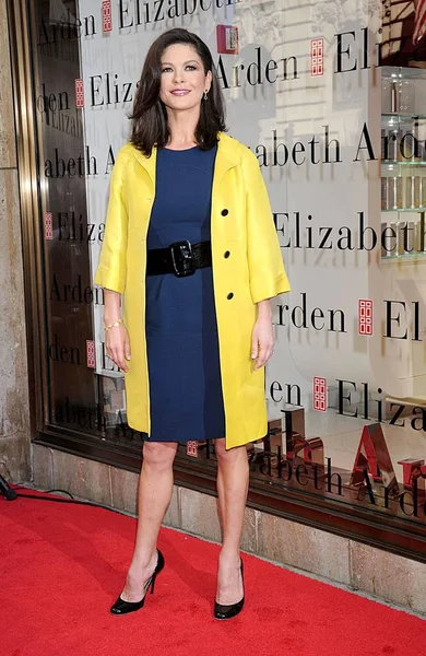 Catherine Zeta-Jones (wearing a Gucci coat, Oscar de la Renta dress, and Brian Atwood heels) at in-store appearance for Elizabeth Arden RED DOOR Global Flagship Store Ribbon Cutting, Elizabeth Arden RED DOOR Fifth Avenue Store, New York, NY, March 06