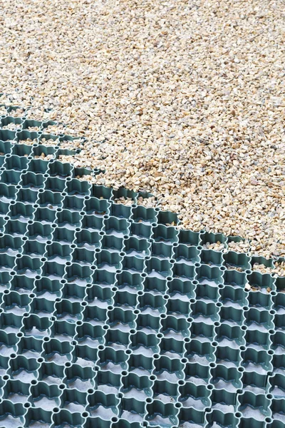 A plastic grid system installed to a gravel driveway protects the ground and prevents the gravel from moving