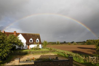 Buckingham, İngiltere - 11 Eylül 2017. Geleneksel bir İngiliz evinin Buckinghamshire, İngiltere'de kırsal üzerinde bir gökkuşağı tarafından çerçeveli