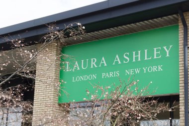 Milton Keynes, UK - March 29, 2018. Trees blossom outside a Laura Ashley store. Shares in Laura Ashley have fallen by almost 90% since 2015. clipart
