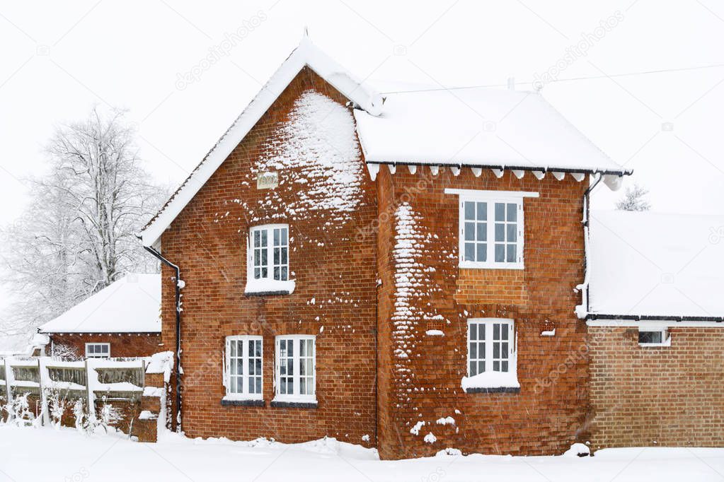 Old Victorian house with roof and brick walls covered in snow in winter