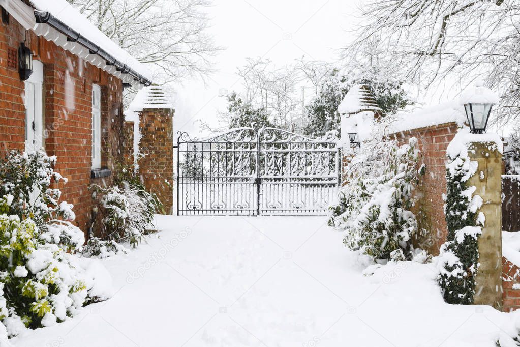 Entrance to Victorian house with cast iron gates with driveway covered in snow in winter