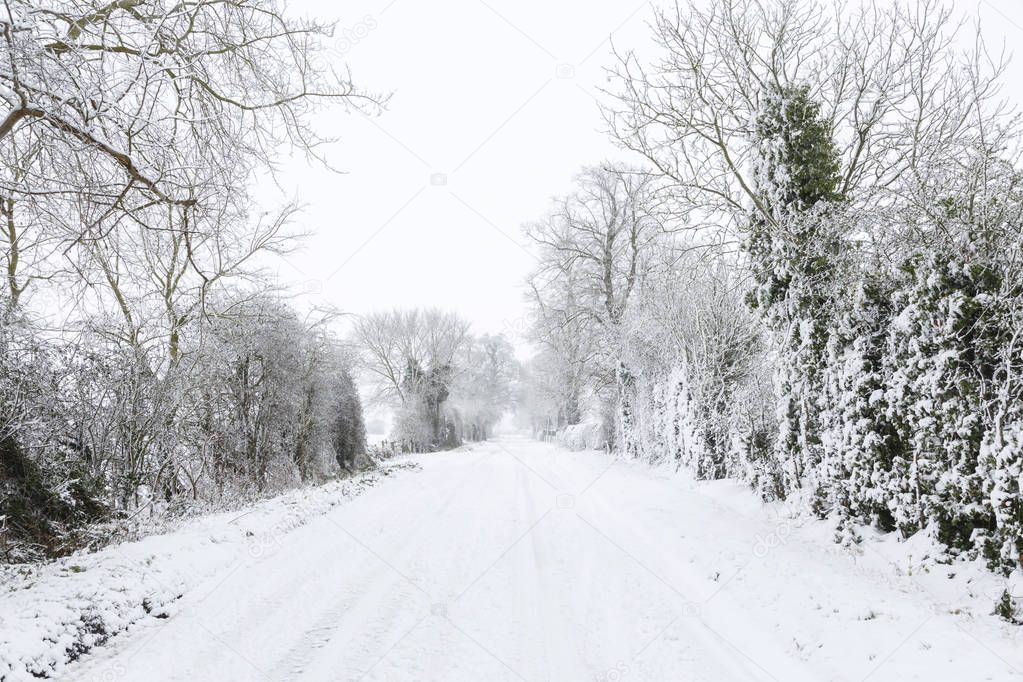 Snow covered road in English countryside in winter. Buckinghamshire, UK