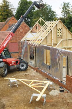 Buckingham, İngiltere - 13 Ekim 2016. Ağır makine çatı makasları Buckinghamshire, İngiltere'de bir ahşap çerçeve ev uzantısı eklemek için kullanılır