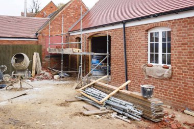 Building site in UK with brick house extension under construction clipart