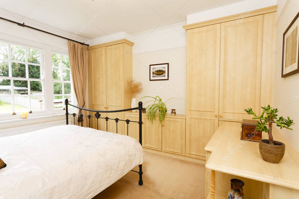 Modern bedroom with neutral colour scheme, cast iron bed and fitted wardrobes