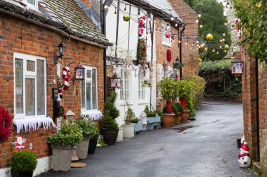 Vintage Christmas street scene in UK town with old cottages, houses and Xmas decorations clipart