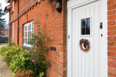 İngiltere 'de lüks bir Viktorya dönemi evinin önünde. Açık beyaz ahşap kapısında Noel çelengi var.