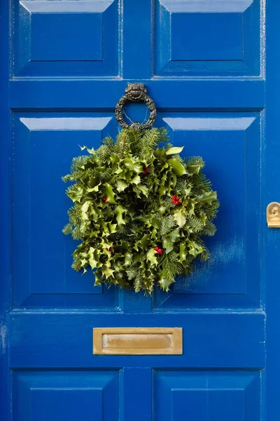 英国冬青制成的带有圣诞花环的蓝色前门的细节 — 图库照片