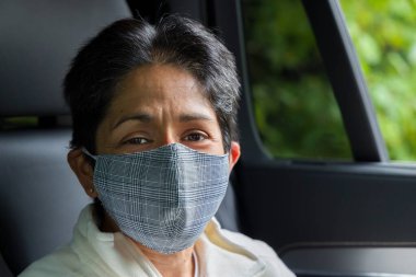 Arabada yüz maskesi takan İngiliz Asyalı kadın (BAME). Birleşik Krallık 'ta COVID veya Coronavirus kavramı, önleme ve kendi kendini izole etme.