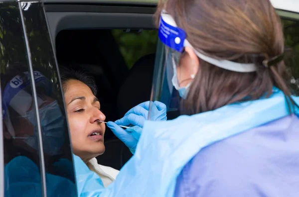 Ppeギアで看護師と車の中でコロナウイルス鼻腔スワブテストを持っているアジアの女性 イギリス イギリス — ストック写真