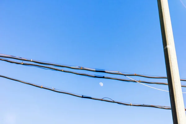 Luna está en el cielo azul entre los cables — Foto de Stock