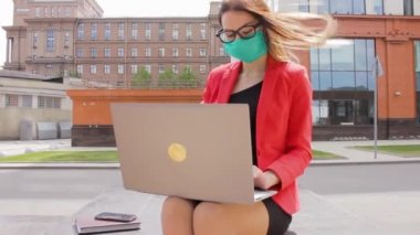 Seksi iş kadını, ofis sokağındaki virüsün yanındaki bir dizüstü bilgisayarda çalışıyor.