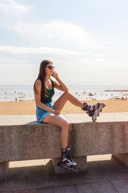 Kız paten kayıyor, telefonda konuşuyor aktif yaşam kondisyonu duraklıyor.