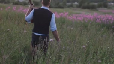 Genç kemancı gün batımında sahada. Doğadan esinlenerek.
