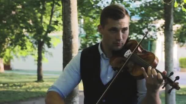 Man violist speelt viool in de steeg in het park en loopt — Stockvideo