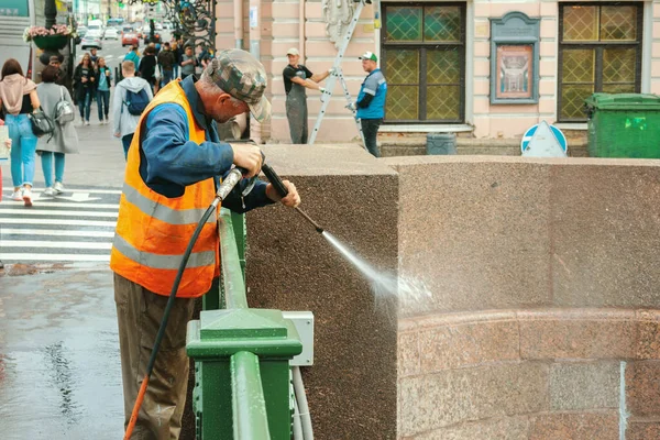 Erkek işçi sokak temizleme kaldırımını yıkıyor su hortumunu yıkıyor