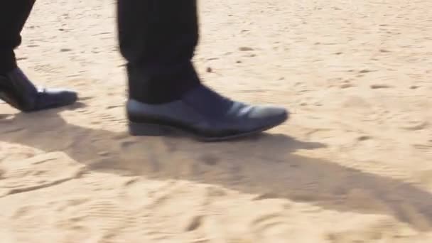 Мужчина в костюме и туфлях едет вдоль пляжа — стоковое видео