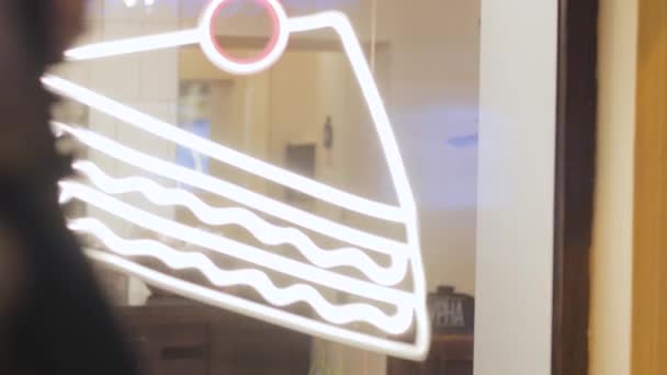 夜のお店の窓にネオンサインおいしいケーキ広告 — ストック動画