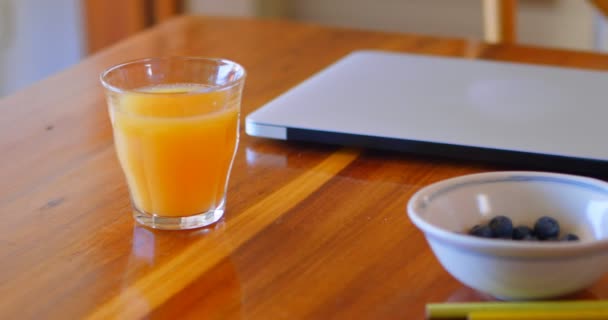 橙色果汁与笔记本电脑 蓝莓和彩色铅笔在家里的桌子上4K — 图库视频影像