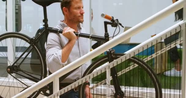 Manliga Verkställande Bära Cykeln Medan Flyttar Övervåningen Kontor — Stockvideo