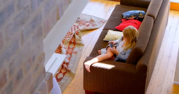 再生女の子ゲーム自宅のリビング ルームで携帯電話で — ストック動画
