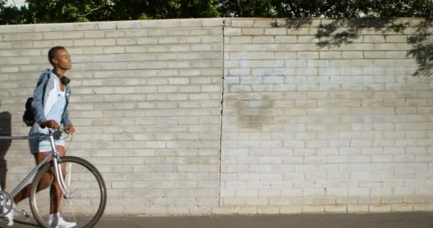 市の歩道で自転車と一緒に歩いている女性 — ストック動画