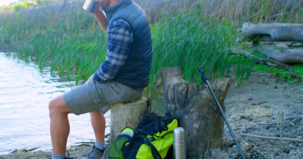 在阳光明媚的日子 在湖边喝咖啡的男性徒步旅行者4K — 图库视频影像