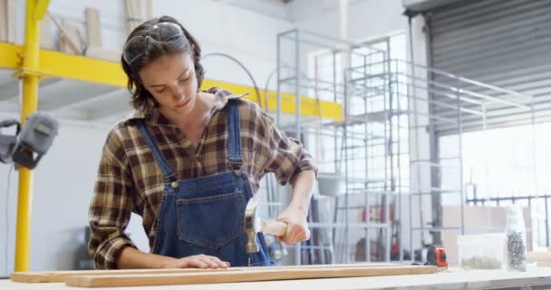 Vrouwelijke Lasser Hameren Spijker Een Houten Plank Workshop — Stockvideo