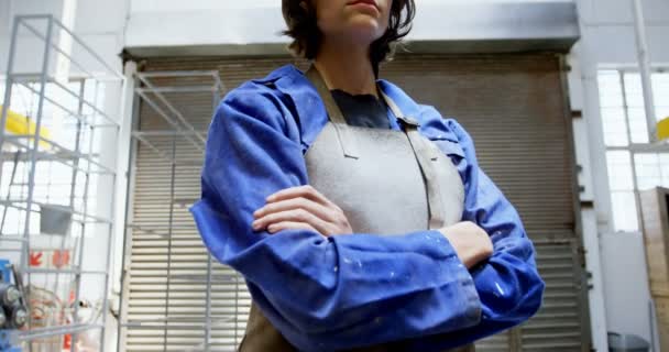 年轻女性焊工站立与胳膊横渡在车间4K — 图库视频影像
