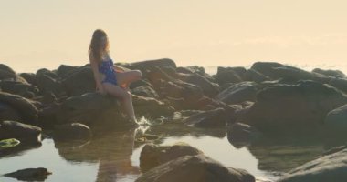 Plajda 4 k kayaya oturan genç kadın