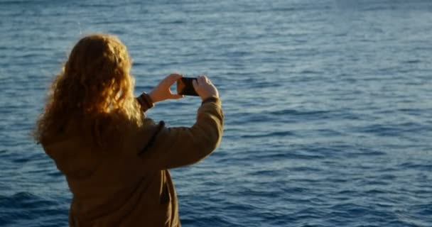 后视图的女人点击照片与手机在码头4K — 图库视频影像