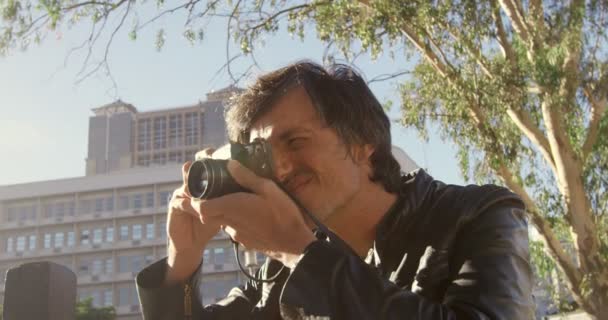 Мужчина Фотограф Фотографирует Городской Улице Солнечный День — стоковое видео