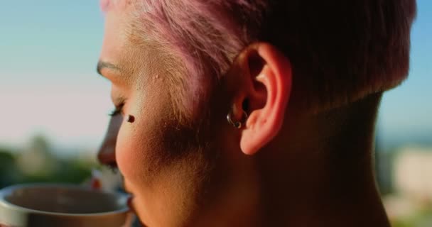 粉红色的头发女人喝着咖啡 看着窗外4K — 图库视频影像