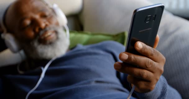 Senior Man Luisteren Muziek Mobiele Telefoon Woonkamer Bij Huis — Stockvideo