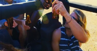 Bira şişeleri 4 k plajda arabada toasting arkadaş grubu