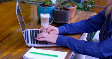 Kadın sahibi 4 k kafede dizüstü bilgisayar üzerinde çalışırken soğuk kahve