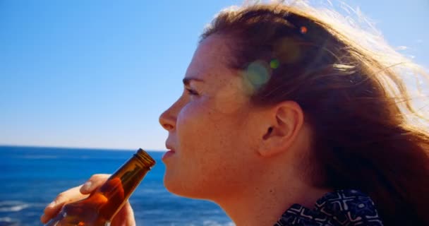 の晴れた日にビーチでビールを持つ女性 — ストック動画